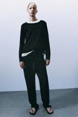 Jersey de punto liso, color azul brillante, con cuello redondo y manga larga. Presenta acabados en rib en puños, cuello y bajo, con aberturas laterales en el ruedo.