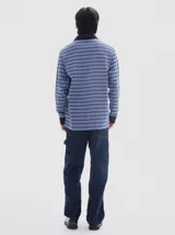 Chomba de manga larga con diseño de rayas horizontales en tonos azules y marrones, con efecto lavado. Presenta cuello polo y cartera de botones en color negro, además de puños negros y bordado pequeño en el pecho.