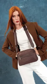 Bandolera de diseño moderno y funcional, confeccionada en nylon color marrón claro. Cuenta con múltiples compartimentos con cierre metálico, herrajes plateados y una correa ancha ajustable con detalle de marca.