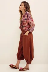 Pantalón bombacho de algodón color marrón, de corte holgado, tiro alto y puños fruncidos en los tobillos. Cuenta con bolsillos laterales.