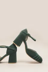 Zapato de tacón color bordó, confeccionado en terciopelo suave, con diseño de pulsera en el tobillo y cierre de hebilla. La punta es cerrada y presenta detalles de líneas cosidas. El tacón es ancho y forrado, con una altura de 7 cm.