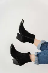 Bota corta de cuero vacuno color negro, con puntera metálica plateada, caña baja, cierre lateral y taco de 7cm. Fabricada en Uruguay.