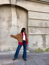 Campera tipo bomber color camel, confeccionada en gamuza, con bordados decorativos en tonos natural y bordó en las mangas y hombros. Presenta cierre frontal y diseño holgado.