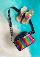 Sandalias de cuero vacuno modelo Anika de Carolina De Cunto, con diseño metalizado de efecto tornasolado en tonos arcoiris, tiras cruzadas y presilla para el dedo. Poseen suela plana y taco bajo de 2 cm.