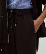 Pantalón de corte recto y calce suelto, confeccionado en tejido de viscosa, poliéster y elastano. Presenta cintura elástica con cordón ajustable con punteras metálicas, recortes frontales y bolsillos traseros.