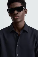 Camisa blanca de manga larga con cuello italiano y cierre frontal de botonadura. Corte regular fit.