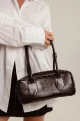 Cartera estilo baguette de cuero color marrón, con doble asa de hombro y cierre de cremallera. Hecha a mano en Uruguay.