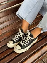 Zapatillas bajas de lona color blanco, con cordones marrones, puntera de goma y base blanca.