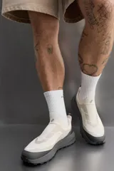 Zapatillas deportivas sin cordones para hombre, color blanco hueso con suela gris. Fabricadas en tejido de punto transpirable con puntera y talón reforzados con material Shield Protect Max. Cuentan con tirador trasero, plantilla OrthoLite® extraíble y entresuela Spume Foam V3.