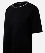 Remera de corte regular confeccionada en gamuza sintética color negro, con mangas cortas y cuello redondo decorado con una aplicación de pedrería brillante.