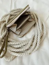 Billetera pequeña de cuero con textura de reptil, color verde pistacho. Cuenta con cierre metálico perimetral, correa de muñeca extraíble y detalle de moneda metálica plateada con logo grabado.