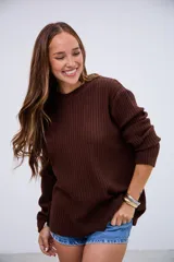 Sweater de punto acanalado color marrón chocolate, con cuello redondo y mangas largas con puños ajustados.