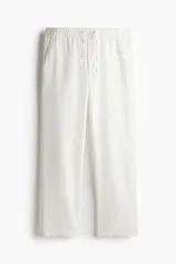 Pantalón de corte relajado confeccionado en una mezcla de lino y algodón. Presenta cintura elástica con cordón de ajuste, bolsillos laterales al bies y bolsillos traseros insertados.