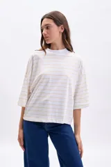 Remera de manga tres cuartos, corte holgado, color blanco con finas rayas horizontales en tono amarillo pálido. Presenta cuello alto tipo mock neck.