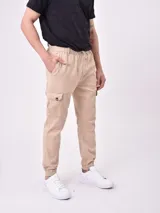 Pantalón jogger color caqui con cintura elástica y cordón ajustable, bolsillos laterales y bolsillos cargo con solapa. Los tobillos tienen puños elásticos.