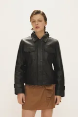 Campera de cuero negro al cuerpo, con cuello camisero, bolsillos de parche con solapa en el pecho y cierre frontal con broches a presión.