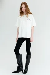 Remera oversized de punto suave de algodón color blanco, con cuello redondo acanalado, hombros caídos y bajo recto. Cuenta con un pequeño estampado tipográfico en azul en el pecho con la frase "La Dolce Vita".