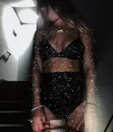 Vestido corto de red con brillos, mangas largas y cuello redondo. Incluye top y short negro.