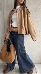 Campera tipo bomber de gamuza con diseño relajado, cierre frontal, cuello camisero y detalles de apliques en los hombros.