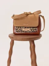Cartera tipo bandolera con solapa de gamuza color tostado, cuerpo con estampado de piel de serpiente y detalle frontal en cuero texturizado color marrón. Incluye correa ajustable y herrajes metálicos.