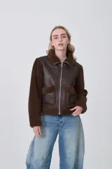 Campera estilo aviador con cuerpo de eco-cuero marrón oscuro y mangas y cuello de corderito (teddy) marrón. Presenta cierre frontal metálico y dos bolsillos frontales con solapa de corderito.