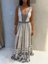 Vestido largo sin mangas con escote en V profundo, falda amplia con vuelo y diseño estampado en tonos blanco y azul oscuro con motivos geométricos y florales.