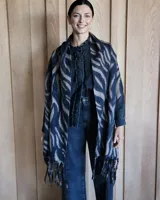 Bufanda de gran tamaño con diseño de estampado animal print tipo cebra en tonos oscuros y neutros, con terminación de flecos en los extremos.