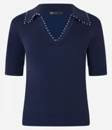 Blusa negra de punto con cuello polo, escote en V y mangas cortas. Detalle de mini perlas aplicadas en el cuello.