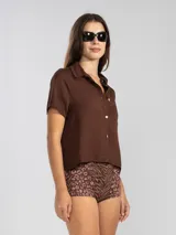 Camisa manga corta color marrón confeccionada en una mezcla de lino y tencel, con cuello camisero y cierre abotonado al frente.