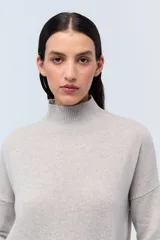 Polera tejida de punto confeccionada en lambswool color gris claro, con cuello alto y calce holgado.