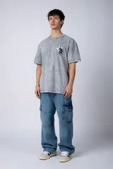 Remera de algodón con efecto acid wash en color gris oscuro. Presenta un diseño estampado en el pecho con una estrella amarilla y un personaje animado, y un corte semi-oversize.