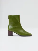 Botas de cuero negro con punta cuadrada, taco ancho de madera y costura decorativa bordada en contraste a lo largo del empeine. Cuenta con cierre en la parte trasera.