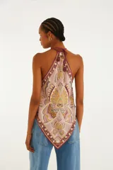Top halter de viscosa con estampado tipo pañuelo en tonos rosados, bordó y beige con detalles florales y geométricos. Presenta corte en punta y tirantes finos para anudar al cuello.
