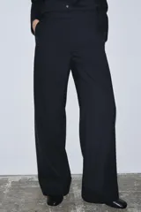 Pantalón de tiro medio confeccionado en lana 100%, con corte de pierna recta y bajo con vuelta. Presenta cintura con trabillas, cierre frontal con cremallera, botón y ganchos metálicos, además de bolsillos laterales y traseros.