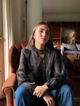 Camisa blanca de manga larga con escote a la base y detalles de blonda en cuello y mangas.