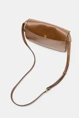 Bolso bandolera de formato alargado en color negro, con solapa frontal y cierre metálico. Incluye una correa ajustable de tejido en color crudo y herrajes dorados.