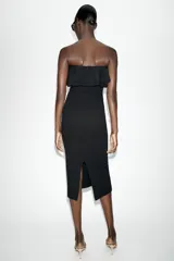 Vestido midi negro de punto con escote de hombros descubiertos adornado con volantes y diseño ajustado.