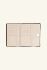 Billetera de cuero con solapa y cierre de broche metálico. Presenta una textura granulada y un pequeño logo grabado en el centro de la solapa.
