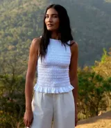 Musculosa blanca con cuello redondo, diseño con lastex y volado en el bajo.