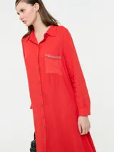 Vestido camisero largo color rojo, confeccionado en lino y viscosa, con cartera de botones delanteros centrales y bolsillo delantero superior con terminación de galón metalizado.
