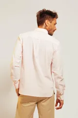 Camisa de vestir blanca de manga larga con cuello abotonado y cierre frontal de botones.