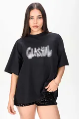 Remerón negro de corte oversize y mangas cortas, con estampa frontal difuminada estilo grafiti adornada con apliques de strass.