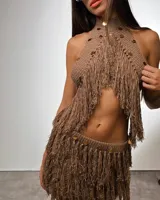 Conjunto de dos piezas tejido en color camel, compuesto por un top halter con flecos y detalles de apliques metálicos circulares, y una pollera a juego con flecos y apliques metálicos en la cintura.