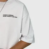 Remera de corte oversize color blanco, con mangas cortas y cuello redondo. Presenta un estampado gráfico minimalista en color negro en el pecho.