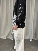 Remera manga larga de algodón color negro, con diseño gráfico abstracto en tono gris en la parte inferior frontal y tipografía cursiva en la manga. Presenta cuello redondo reforzado y grifa de la marca en el puño.