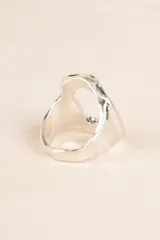 Anillo plateado con forma geométrica irregular y diseño moderno.