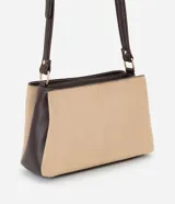 Cartera bandolera de tamaño mediano con diseño bicolor que combina paneles de gamuza sintética en color beige con laterales y correa en cuero sintético marrón oscuro. Cuenta con asa larga ajustable y tres compartimentos internos para organización.