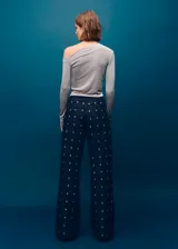 Jeans wide leg de tiro medio, confeccionados en denim azul oscuro con apliques de cristales distribuidos en toda la prenda. Cuenta con diseño de cinco bolsillos, trabillas para cinto y cierre frontal con botón y cremallera.