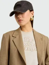 Remera de algodón color crema con cuello redondo y mangas cortas. Presenta una estampa frontal con la frase 'The Golden Dreamers' en letras doradas con contorno marrón.