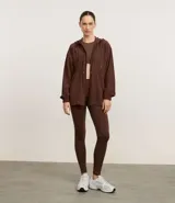 Campera parka de estilo deportivo con capucha, cierre frontal por cremallera, cintura ajustable con cordón y mangas largas con puños elásticos. Presenta un diseño funcional con bolsillos delanteros y ruedo redondeado.